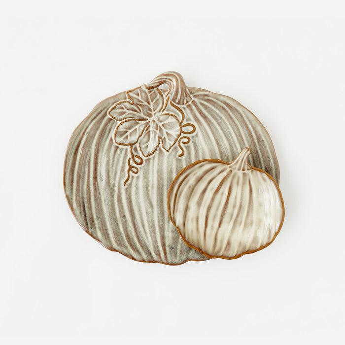 A decorative ceramic pumpkin-shaped plate or tray with a ribbed surface, a floral vine motif near the top, and a smaller overlapping pumpkin figure, shown on a plain white background.