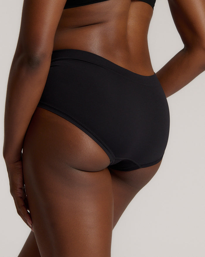 Person wearing black high-waisted underwear on a plain background