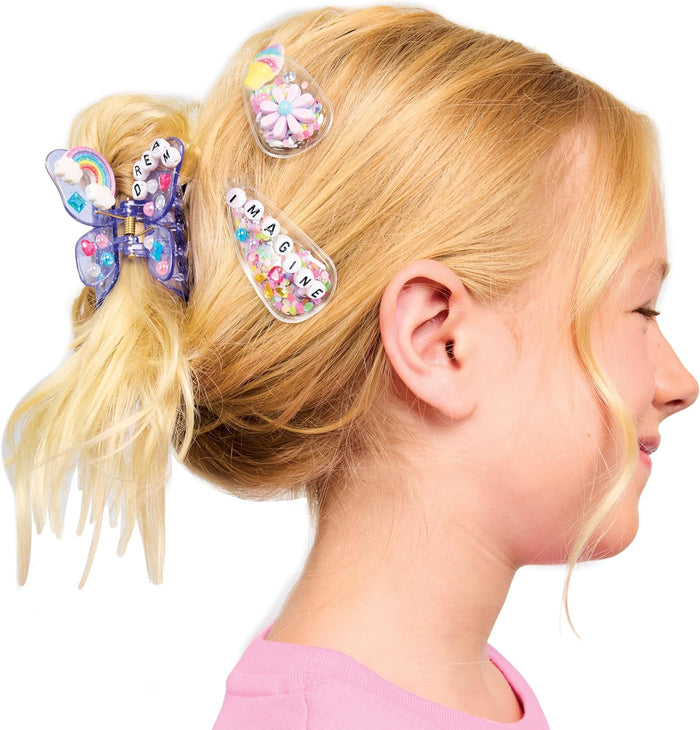 Three hair clips, decorated, in a young girls hair.