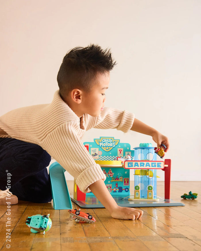 Young boy playing with Crazy Motors Garage and Crazy Motors cars on a wooden floor