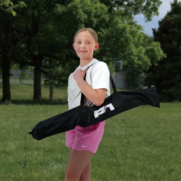 Young girl holding a black bag with a logo in a park setting.The bag contains the Fold and Go Soccer Goal.