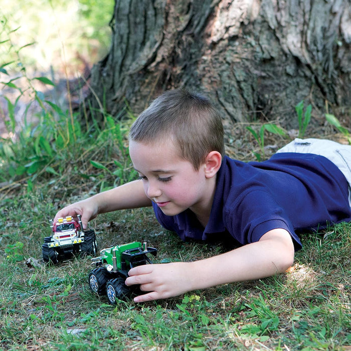Child playing with toy trucks in a grassy area near a tree