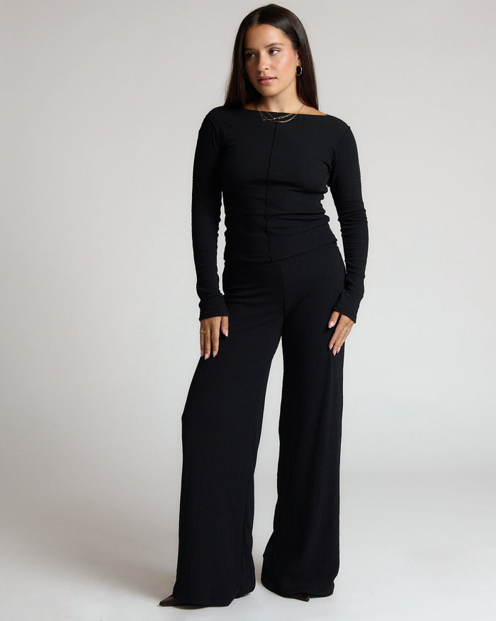Woman wearing a black outfit on a plain background