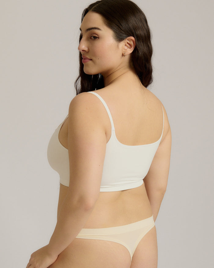 Woman wearing a white bra and white underwear on a plain background