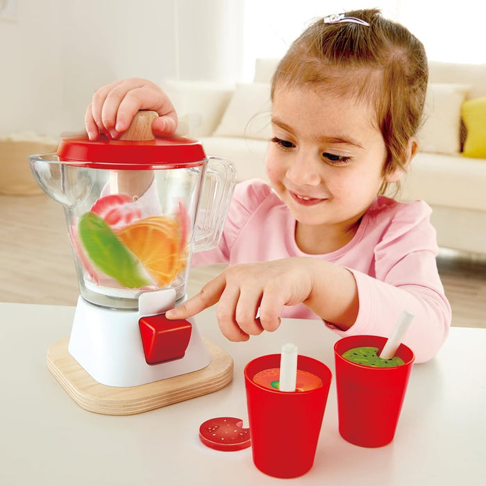 Child playing with a toy blender and cups on a table.