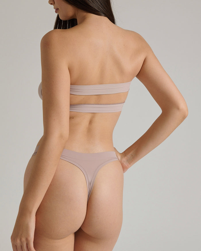 Woman wearing a beige strapless against a plain background