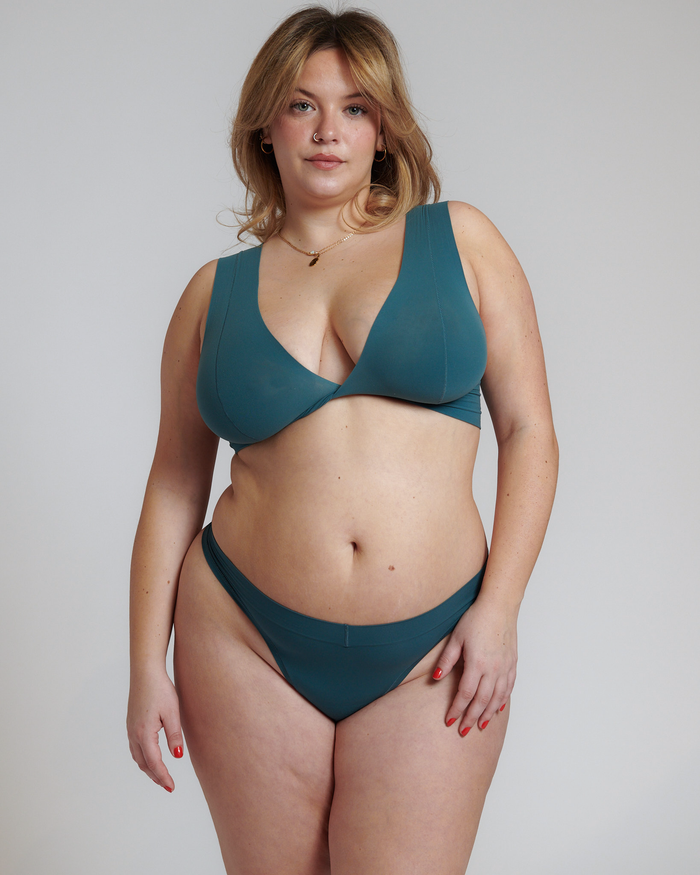 A person wearing a jade green Twist System bra with a wide band and single straps