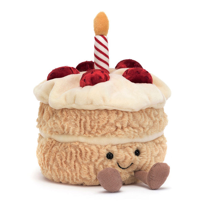 Plush toy resembling a birthday cake with a candle on a white background
