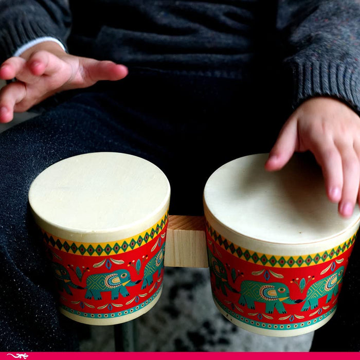Child in a dark sweater playing the wooden bongos on a table top