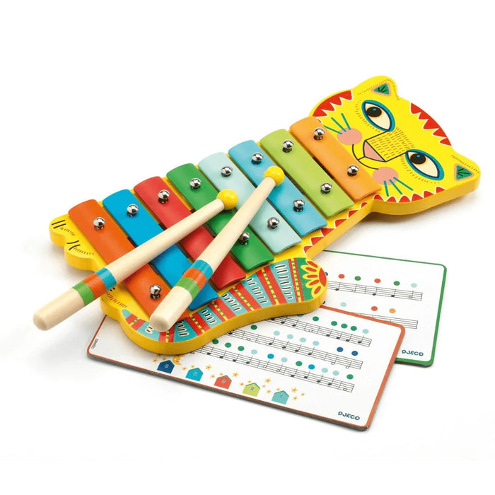 Colorful children's xylophone with a cat face and drumsticks and music sheet on a white background