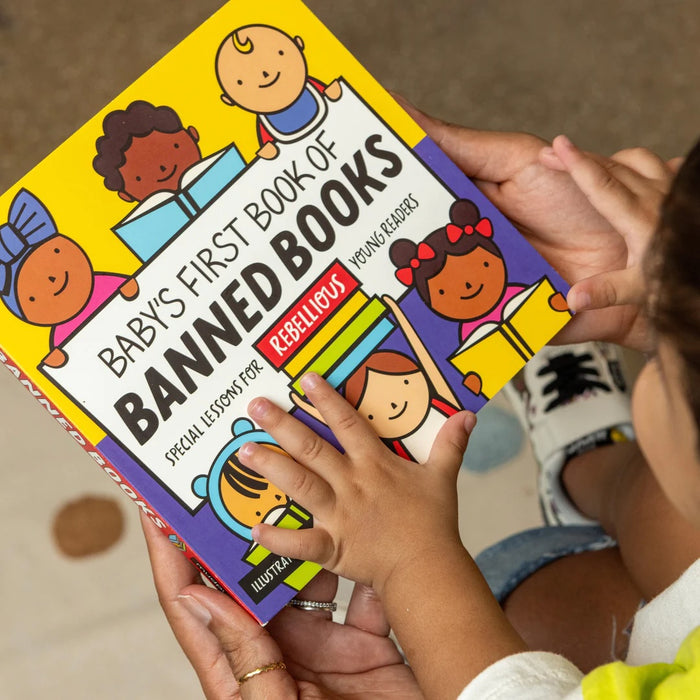 Parent and child holding a copy of 'Baby's First Book of Banned Books'
