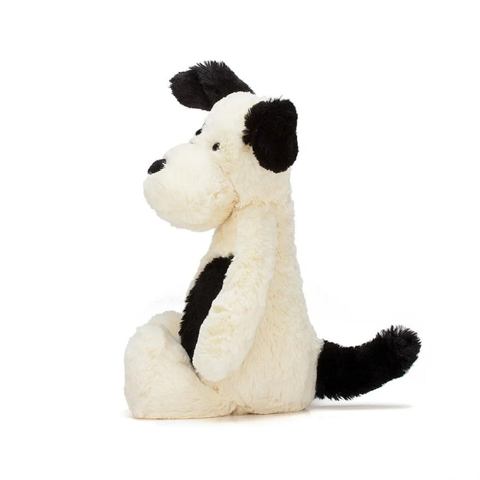 Side view of a black and white plush dog toy on a white background