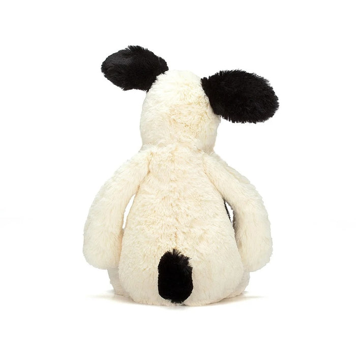 Rear view of a black and white plush dog toy on a white background