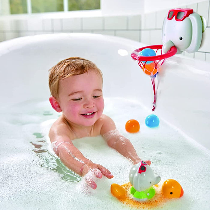 Child playing in a bathtub with colorful bath toys and a toy elephant.