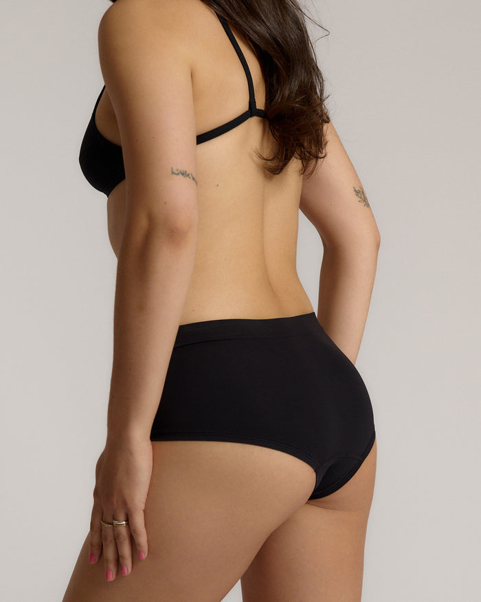 Person wearing black high-waisted underwear on a plain background