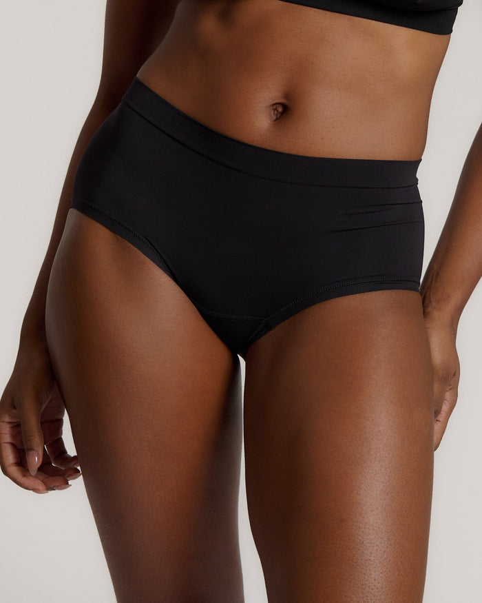 Person wearing black high-waisted underwear on a plain background