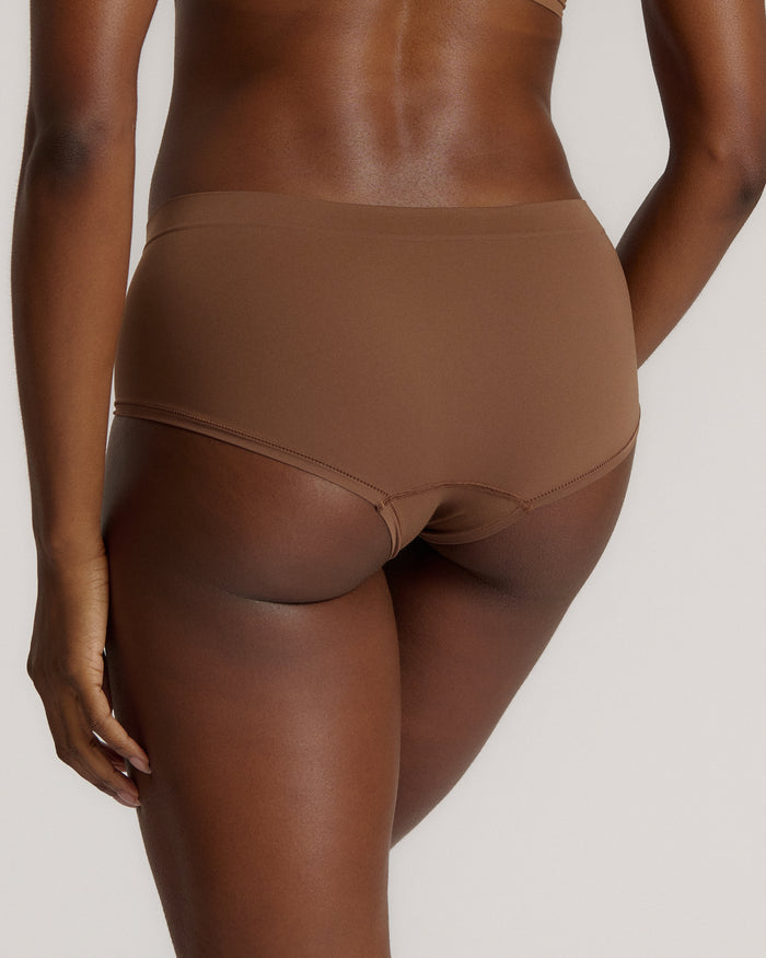 A mid-rise brown brief underwear with a seamless design, showing the waistband and part of the leg openings.