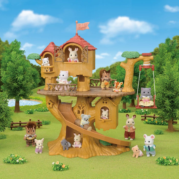 A Calico treehouse playset with various animal figurines, set in a simulated forest environment with green grass, trees, and a blue sky.