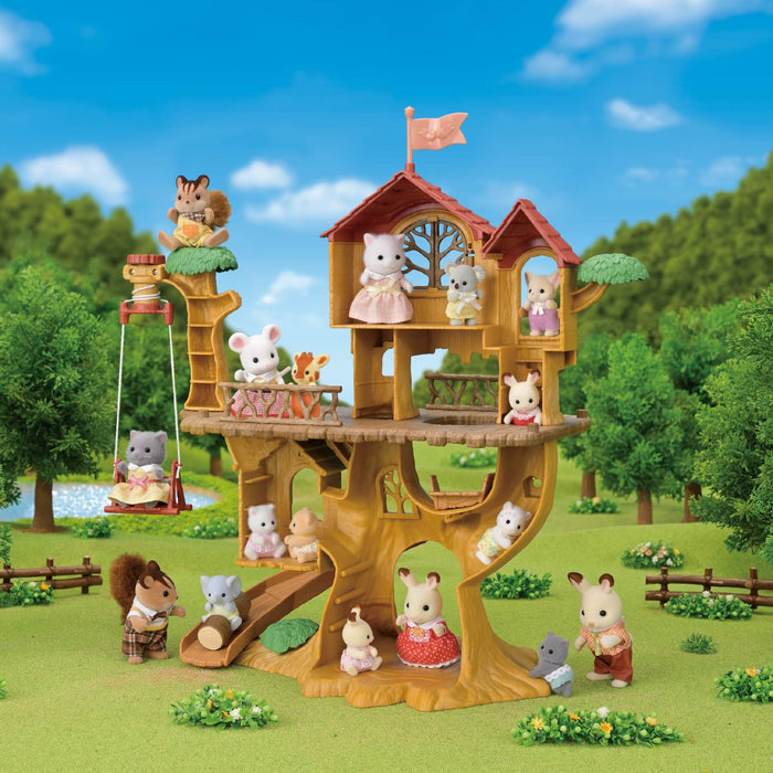 A treehouse playset with multiple animal characters arranged around and inside the wooden treehouse in a landscaped garden scene with trees, grass, a swing, and a blue sky background.