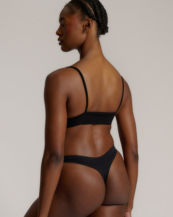 Person wearing a black cami system against a plain background
