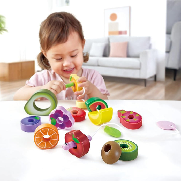 Child playing with the Caterpillar Fruit Feast Set on a white table in a living room.