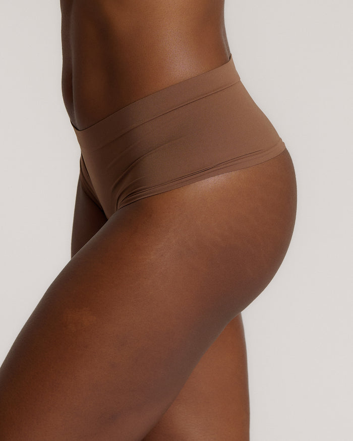 A person wearing a pair of brown, mid-rise women's underwear.
