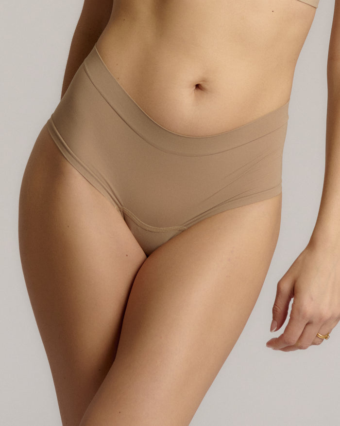 A pair of beige, mid-rise women's underwear.