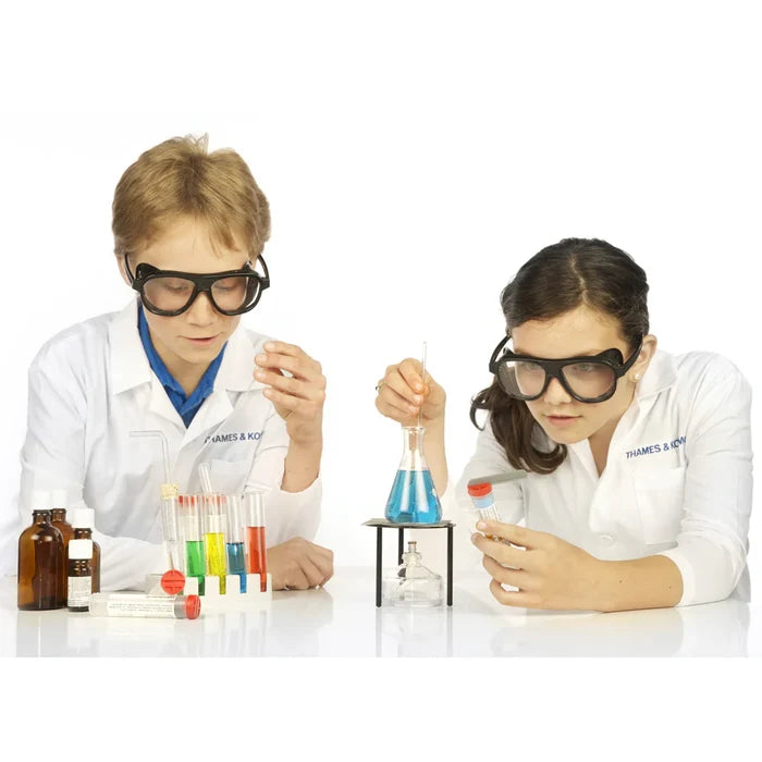 Two children in lab coats conducting a science experiment with colorful liquids in beakers.