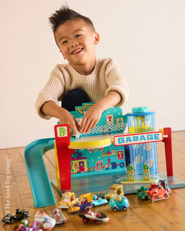 Young boy playing with Crazy Motors Garage and Crazy Motors cars on a wooden floor