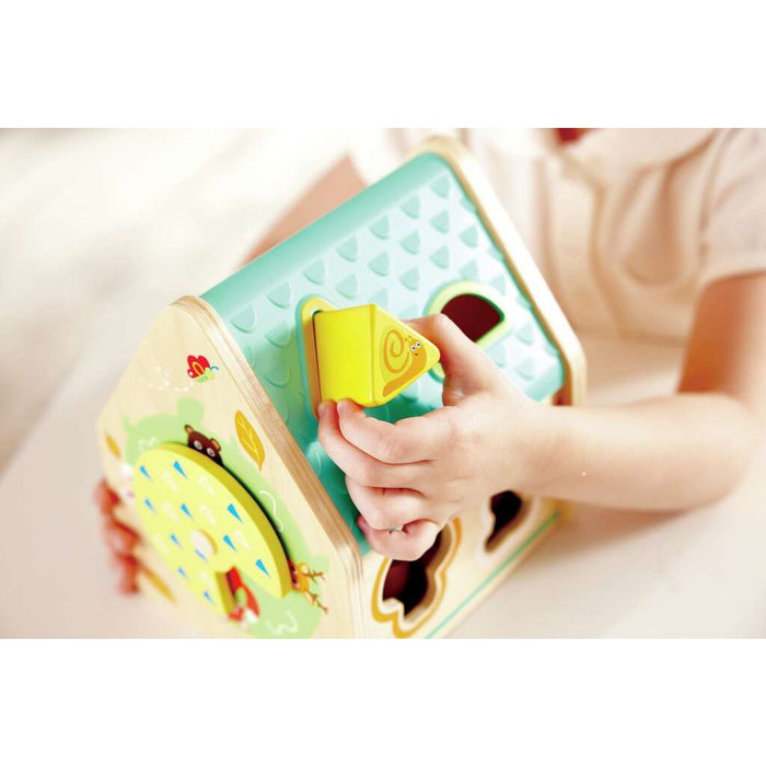 Child putting a yellow triangular shape into the Critter House Shape Sorter