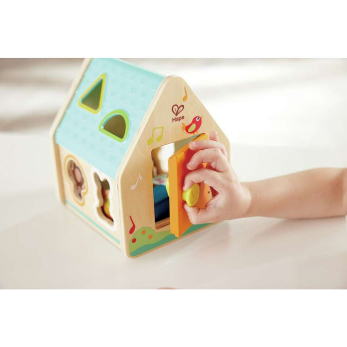 Child opening the door to the Critter house Shape Sorter on a white table