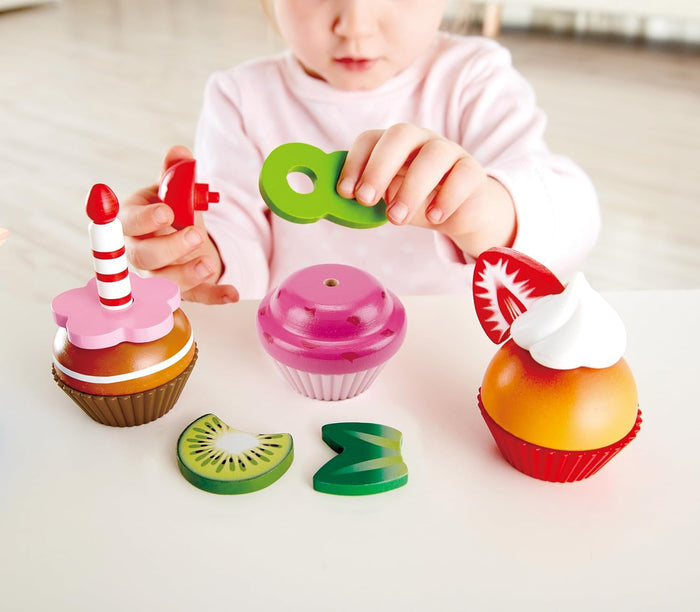 Child playing with colorful toy cupcakes and letters on a light surface