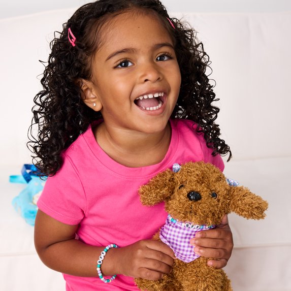 Child holding a brown dog plush with a white background