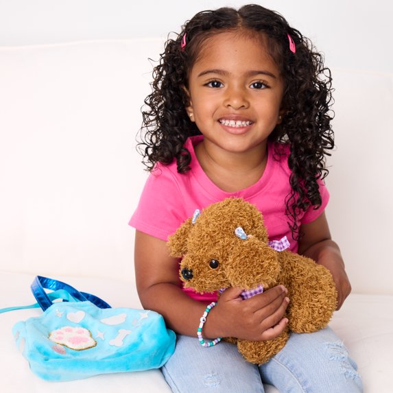 Young girl holding a brown dog with a blue bag on a white background