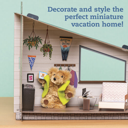 Miniature vacation home with teddy bear, plants, and decor against a light blue wall.