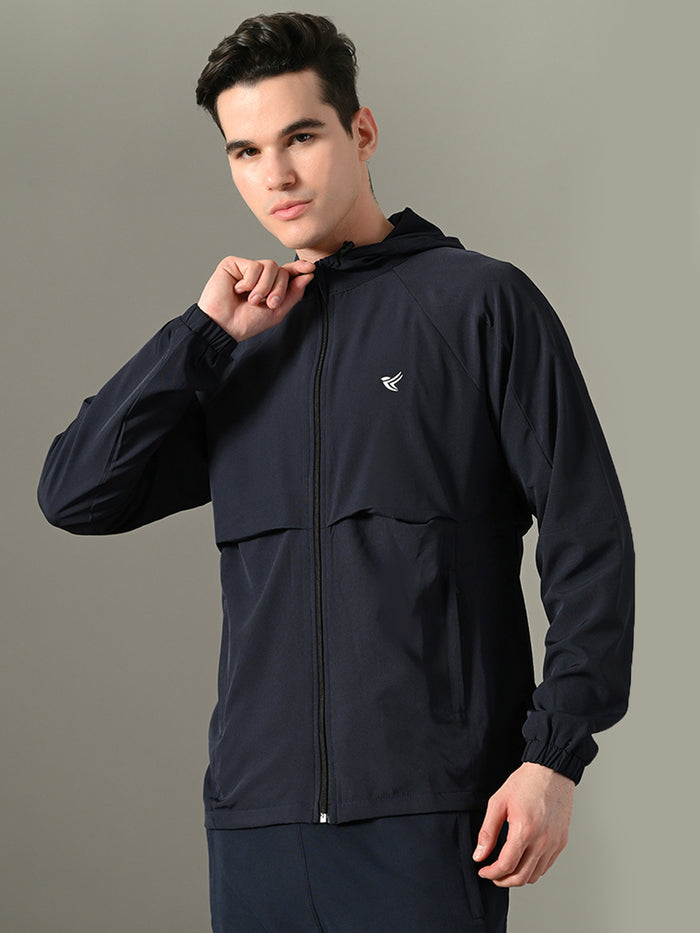 Man wearing a black jacket with a logo on a gray background