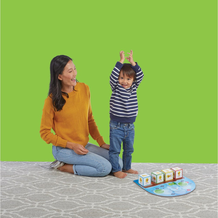Mother and child playing Duck Duck Dance on a grey carpet and bright green background.