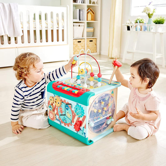 Two children playing with a colorful activity center in a bright, well-lit room.