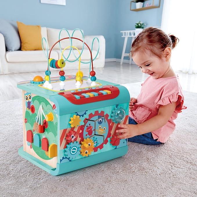 Child playing with the Explore and Learn Cube on a grey carpet in a living room