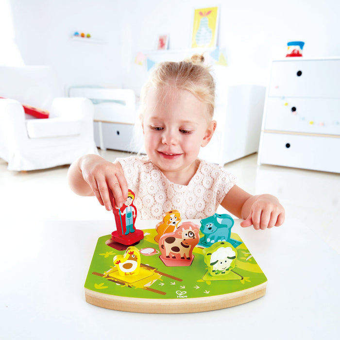 Child playing with a colorful wooden animal farm puzzle in a bright room