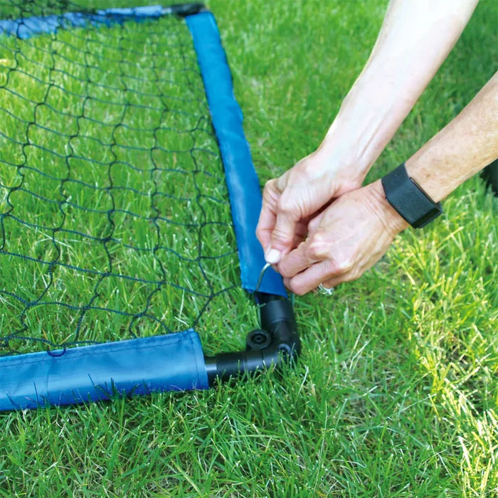 Person attaching the frame of the Goal onto grass.
