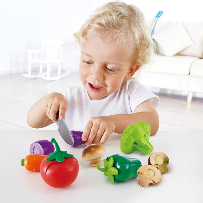 Child playing with colorful toy vegetables on a light surface