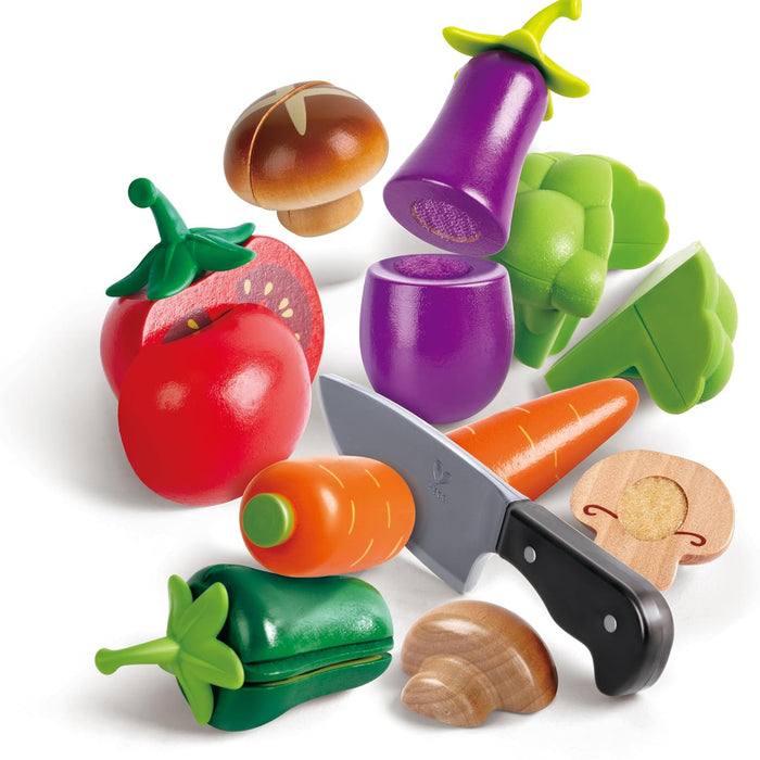 Set of toy vegetables including a carrot, tomato, pepper, mushrooms, and a pretend knife on a white background