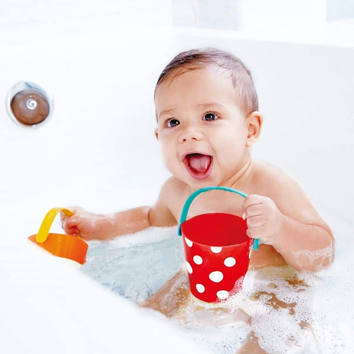 Baby playing in a bathtub with two happy buckets.