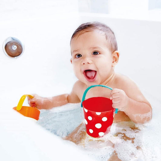 Baby playing in a bathtub with two happy buckets.
