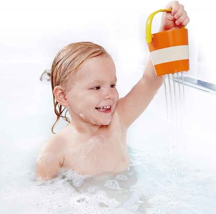 Child in soapy bathtub playing with a happy bucket.