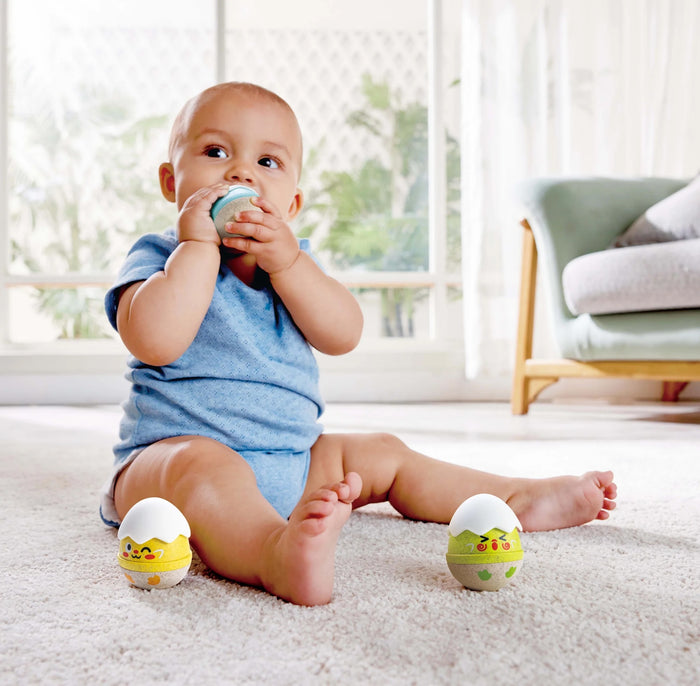 Baby sitting on a carpeted floor with colorful toys in a bright room.
