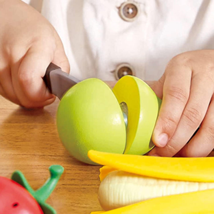 Close up of a child cutting play fruit with a pretend knife on a wood table