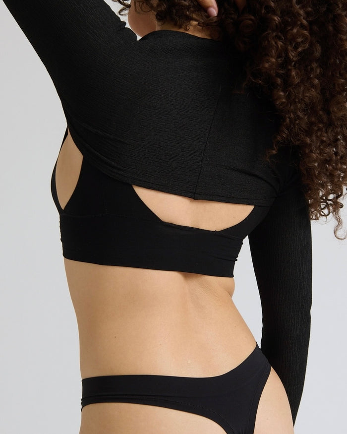 Person wearing a black bra and bolero on a plain background
