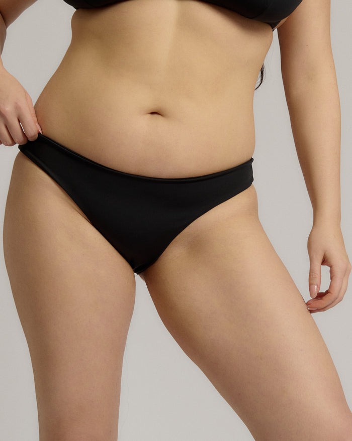 Person wearing a black bikini bottom against a neutral background